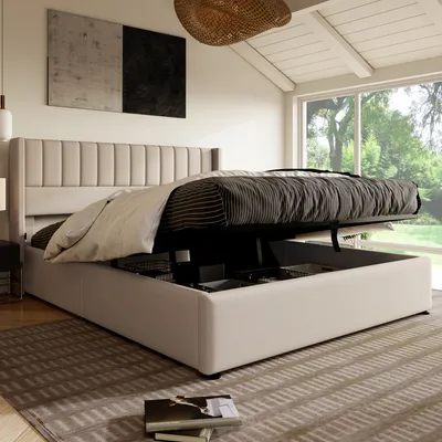 A modern bedroom with a beige upholstered bed with storage, large window with a garden view, and abstract art on the wall.