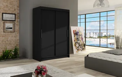 A bedroom scene with a black wardrobe, bed, and artwork.