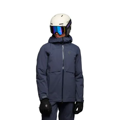 Dame trägt die "Factor Shell" Hardshelljacke von Black Diamond; ausgestattet mit Helm und Skibrille.