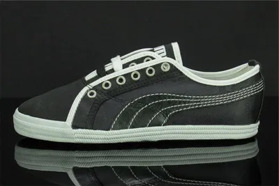 A black Puma sneaker with white accents is shown against a black background.