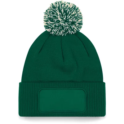 A green beanie with a white and green pom-pom and a rectangular patch on the front.