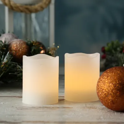 Two LED candles and a Christmas ornament on a wooden surface with a blurred background.