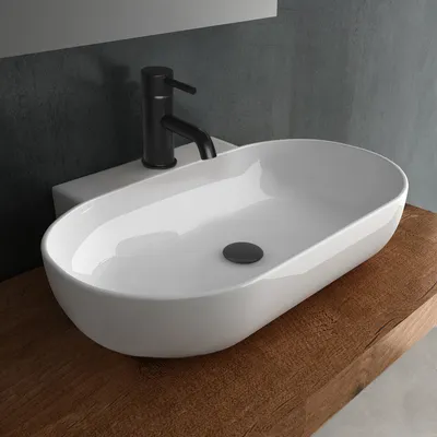 A white ceramic washbasin with a black faucet is placed on a wooden countertop.