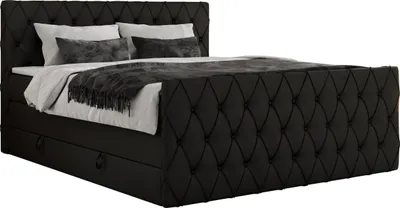 A black upholstered boxspring bed with a tufted headboard and side panels, shown with pillows and a blanket.