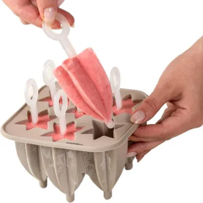 A person is removing a strawberry popsicle from a popsicle mold.