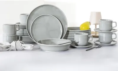 A collection of grey porcelain dinnerware, including plates, bowls, and cups, arranged on a white surface.