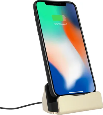 A smartphone charging on a gold charging stand.