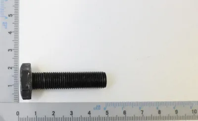 A black bolt is placed on a white surface next to a ruler.