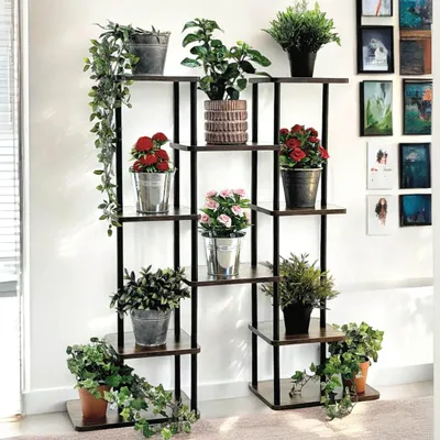 A multi-tiered plant stand with various potted plants displayed on its shelves, set against a white wall.