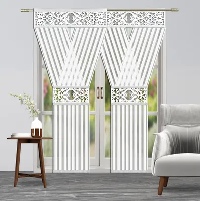 A pair of white striped curtains with decorative silver bands and a white vase with flowers on a small wooden table.