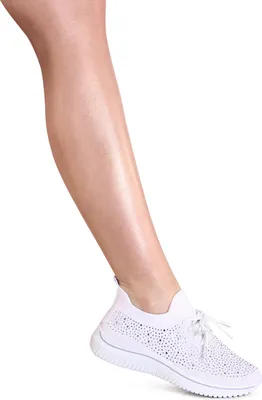 A close-up shot of a woman's lower leg and foot wearing a white sneaker.