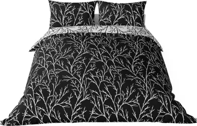 A bedding set with a black background and a white branch pattern, displayed on a bed.