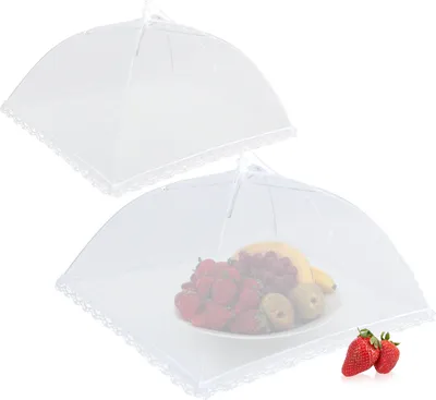 Two white mesh food covers, one empty and one covering a plate of fruit.