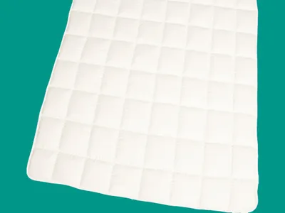 A white quilted mat is shown against a teal background.