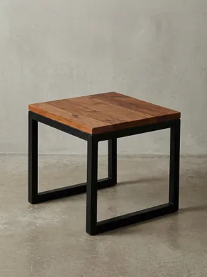 Freigestellter Beistelltisch im Industrial Style mit einer massiven Sheesham-Holzplatte und einem kubischen, schwarzen Metallgestell, Frontansicht auf weißem Hintergrund._#sku_BARWL6.150#