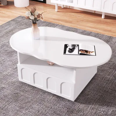 A white, cloud-shaped coffee table with a book and vase on it, placed on a gray rug in a living room.