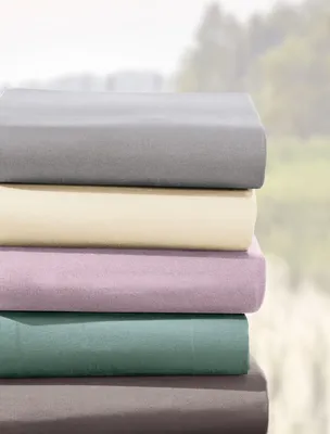 A stack of folded sheets in various colors against a blurred outdoor background.
