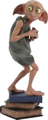 A Dobby figurine from Harry Potter standing on a stack of books.