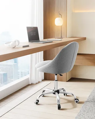 A grey office chair positioned at a wooden desk in front of a large window.