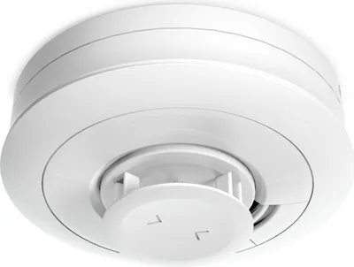 A white smoke detector mounted on a white ceiling.
