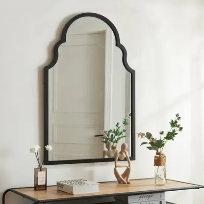 A mirror is displayed on a console table with decorative items.