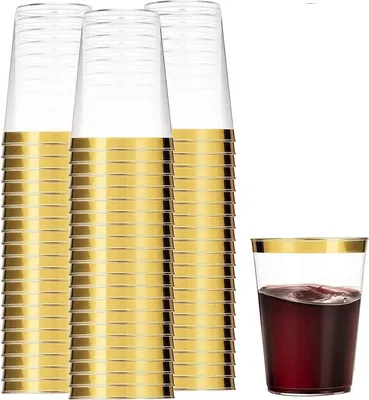 A stack of clear plastic cups with a gold rim, and one cup filled with red liquid.