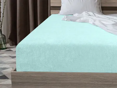 A close-up view of a mint green fitted sheet on a bed.