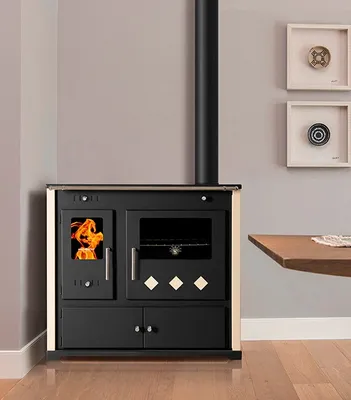 A wood-burning stove with an oven and a ceramic hob, shown in a room setting with a table and wall decorations.