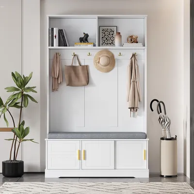 A white entryway hall tree with a bench and storage cabinets, decorated with a plant, books, and accessories.