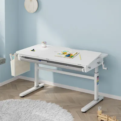 A white height-adjustable desk for children is shown in a room with light blue walls and a wooden floor.