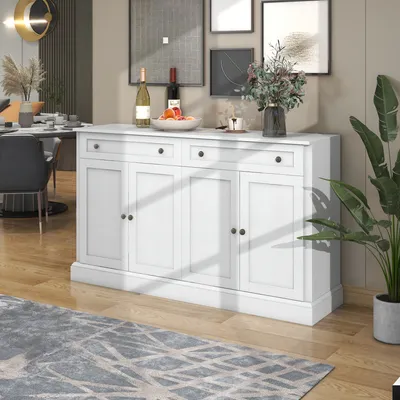 A white sideboard with drawers and doors is placed in a dining or living room setting, with a rug in the foreground and artwork on the wall behind it.