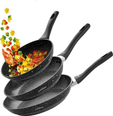 Three frying pans are stacked on a white background, with chopped vegetables and shrimp falling into the top pan.