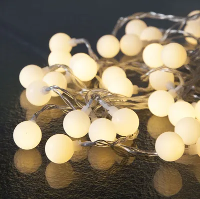A close-up shot of a string of white LED party lights with a dark, reflective background.