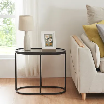 A side table with a lamp and a framed picture next to a sofa.