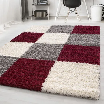 A shaggy rug with a checkered pattern in burgundy, white, and gray, laid out on a light-colored floor.