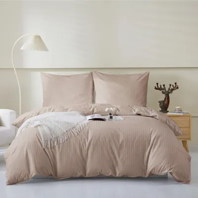 A neatly made bed with beige bedding and pillows, a white throw blanket, and a book.