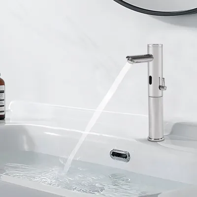 A modern silver faucet with an infrared sensor is dispensing water into a white sink.