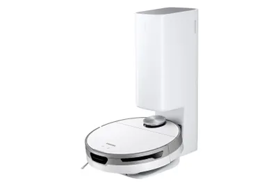 A white robot vacuum cleaner is docked in its charging station against a white background.