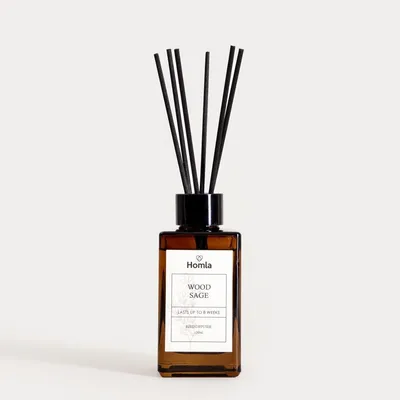 A brown glass diffuser bottle with black reeds and a white label.