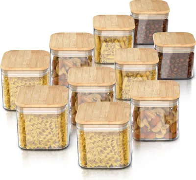 A collection of glass storage containers with bamboo lids, filled with various food items like pasta and coffee beans, arranged on a white background.