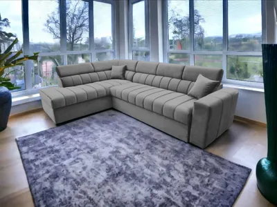 A sectional sofa is placed in a sunroom with large windows overlooking a landscape.