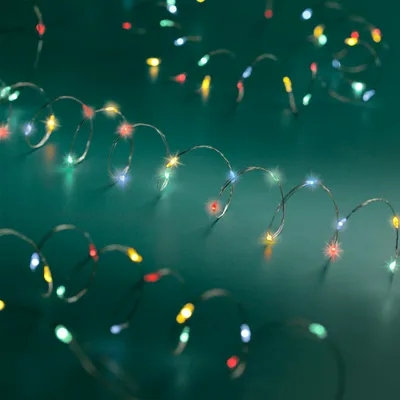 A close-up shot of a string of colorful LED lights coiled on a teal surface.
