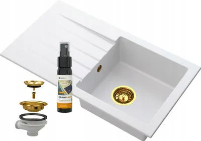 A white kitchen sink with a drainboard and gold-colored drain assembly and faucet parts, along with a cleaning spray bottle.