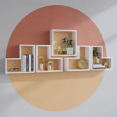 A set of white wall shelves with various decorative items and books arranged on them, mounted on a wall with a large circular design in pink and orange.