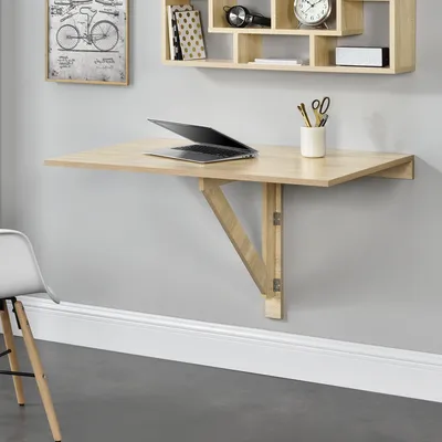 A wall-mounted folding desk with a laptop and office supplies.