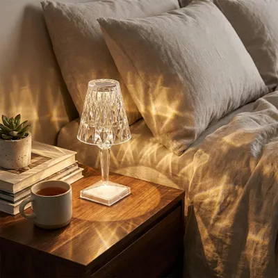 A bedside table with a lamp, a cup of tea, and books.