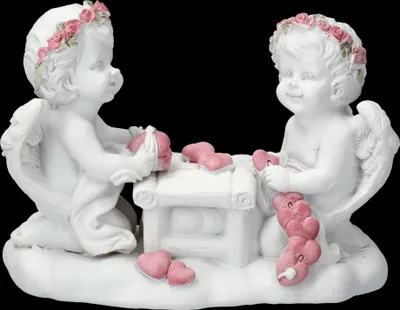 Two white cherub figurines are kneeling and crafting with pink hearts.