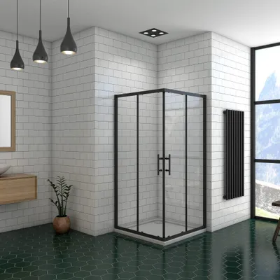 A modern bathroom with a corner shower enclosure, white tiled walls, and green hexagonal floor tiles.
