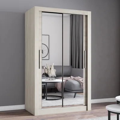 A wardrobe with mirrored doors is shown in a room setting with a sofa and coffee table reflected in the mirrors.