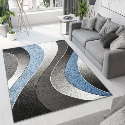 A modern living room with a gray sofa and a rug with a wave pattern in gray, black, and blue.
